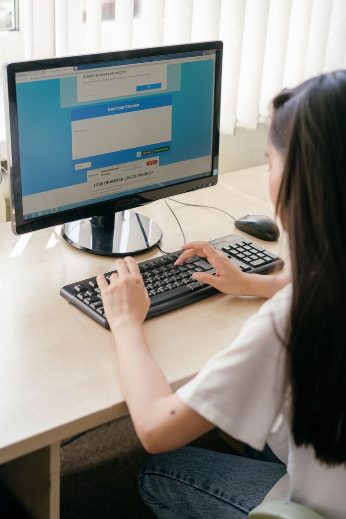 Home A student typing on a computer in a bright classroom for e-learning or research.