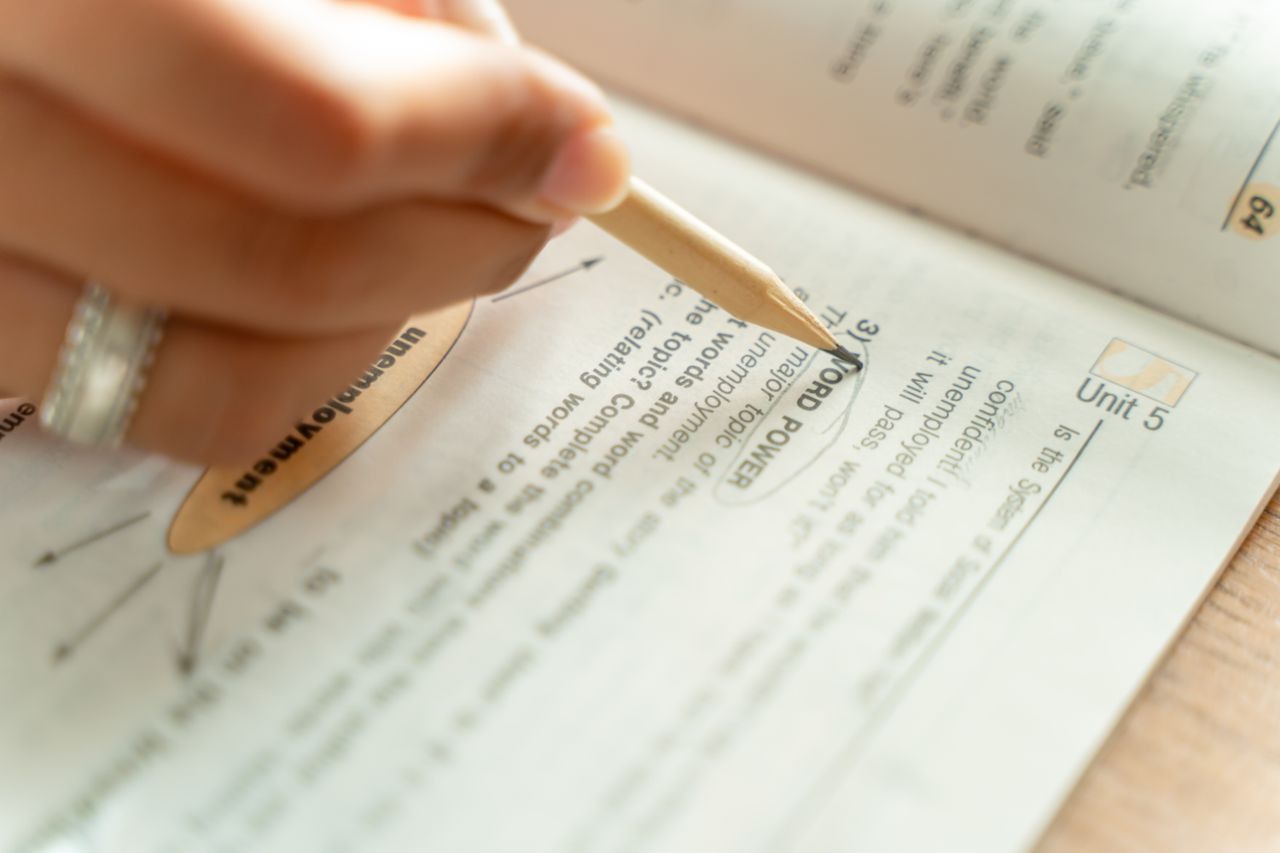 Home Close-up of a woman writing notes in a textbook, focusing on education and learning.